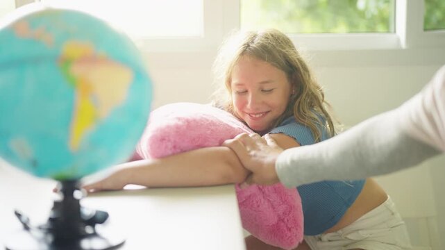 School teacher teaching young girl geography with globe during interactive classroom lesson supporting elementary education global awareness curiosity communication active learning in primary school