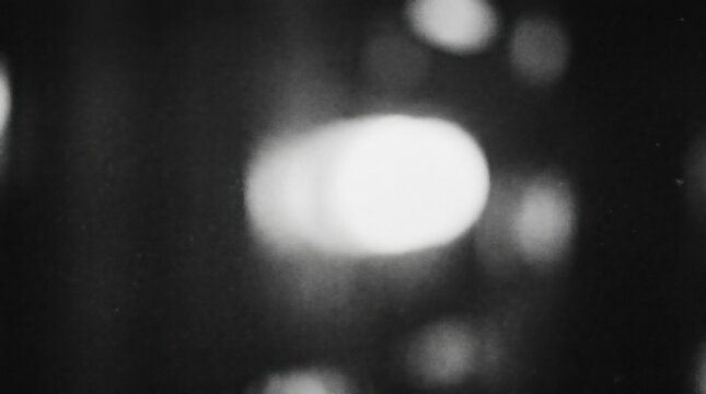 Abstract black and white blurred bokeh light orb with heavy grain texture