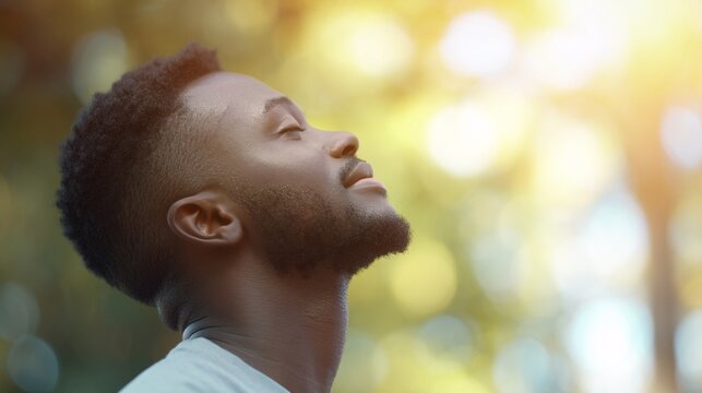 Joyful african man smiling with his eyes shut basking in sunlight radiating positivity and tranquility