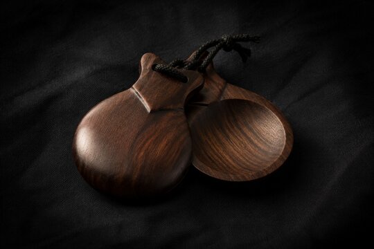 Traditional flamenco castanets resting on dark textured fabric.