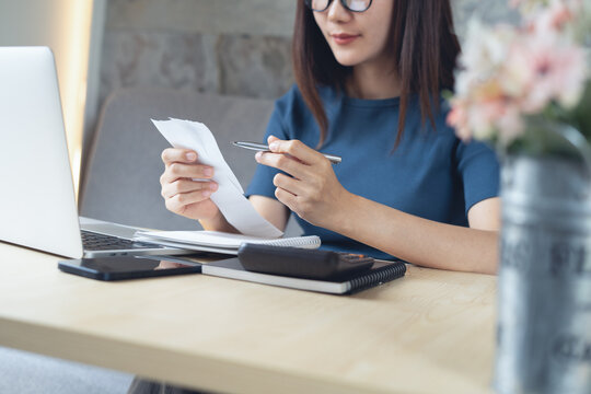 Close up business woman checking payment invoice bill, doing home finance, accounting with laptop on office table, budget planning and tax calculation