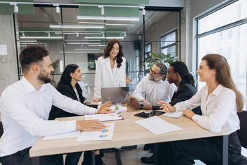 Fototapeta premium Diverse business team collaborating in a modern office, manager leading a discussion with colleagues around a meeting table