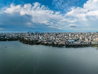 Fototapeta premium Aerial shot of Hangzhou city, West Lake and surrounding mountains framed under white clouds