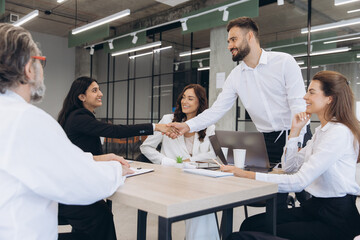 Fototapeta premium Business team members shake hands in a modern office, collaborating to finalize an agreement in a thriving corporate setting