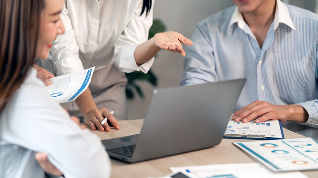Group of Asian business people collaborating and working together on a laptop in office.