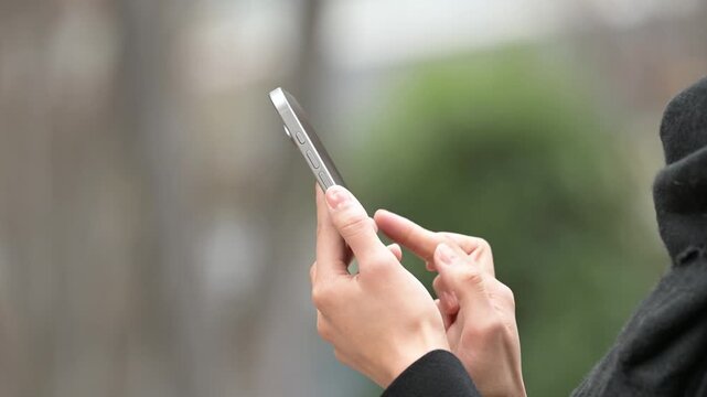 冬の屋外でスマートフォンを操作する女性の手元