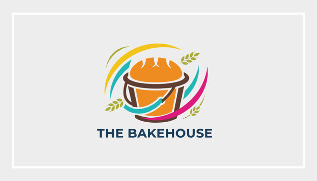 Creative bakery logo design featuring a fresh loaf of hot bread in a basket with colorful wheat ears around it.