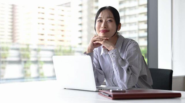 窓際でノートパソコンを使って仕事をする30代の日本人ビジネスパーソンの女性