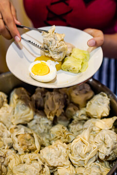 Indonesian siomay dumplings being served with tongs close up street food