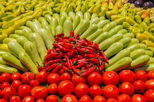 Colorful arrangement of fresh vegetables including zucchini, peppers, chili and tomatoes at Tajik harvest festival market
