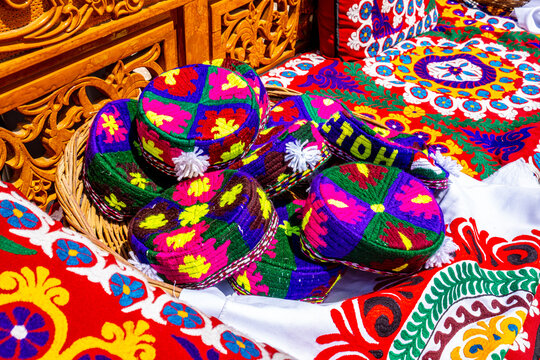 Traditional Central Asian colorful embroidered textiles and decorative items displayed at Tajik market stall, cultural heritage concept