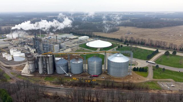 Aerial view of ethanol industrial plant with silos and smokestacks emitting steam.