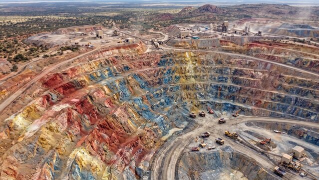 Drone Shot of Deep Multicolored Terraced Open Pit Mine with Heavy Machinery Operating