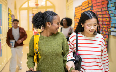 Obraz premium Diverse students walking together in university corridor, enjoying friendship and education