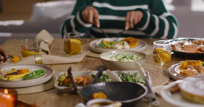 Diverse female companions placing knife and fork, cutting food and sharing meal at wooden table