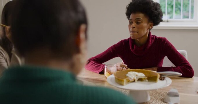 Diverse female friends sharing cake at home, African American woman cutting slice for sharing