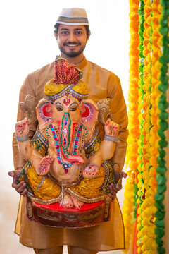 Portrait of a Maharashtrian man carrying statue of Lord Ganesh