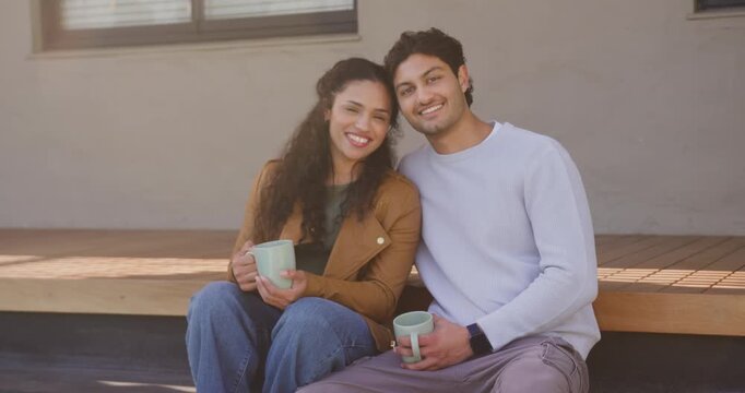 African American couple on porch bench smiling at camera turning, holding mugs, talking to connect