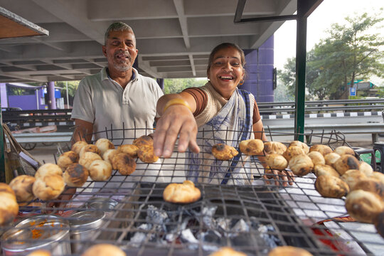 Senior couple making litti at his roadside food stall