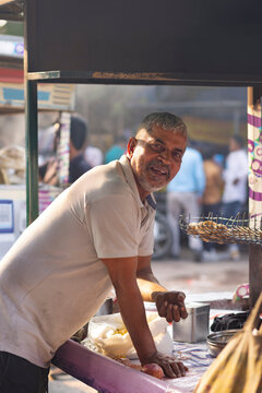 Portrait of male vendor looking at camera while standing at his roadside food stall