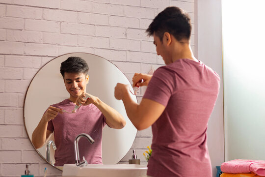 Young man squeezing out toothpaste on a toothbrush