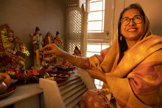Portrait of senior woman performing pooja of Hindu God at home