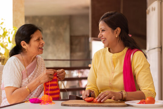 Mother-in-law and daughter-in-law talking while doing housework on balcony