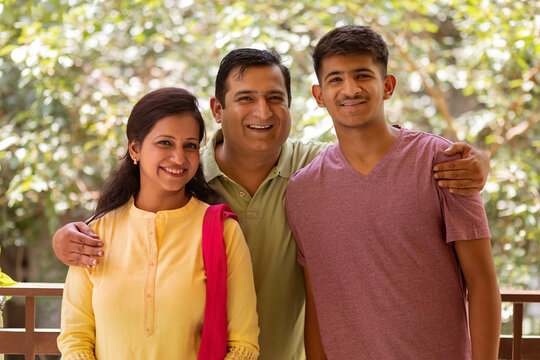 Portrait of happy parents with their son standing together on balcony