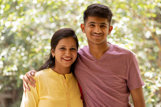 Portrait of happy mother and son standing together on balcony