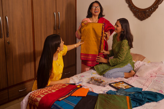 Woman selecting sari with the help of her granddaughters while getting ready for a traditional festival