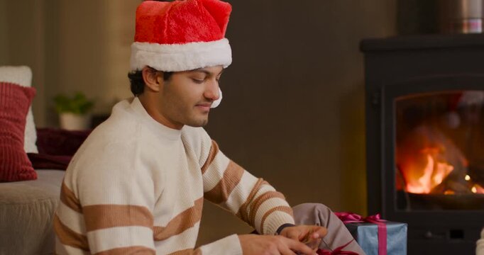 African American couple in Santa hats, man untying ribbon, woman offering twine, tying tag by stove