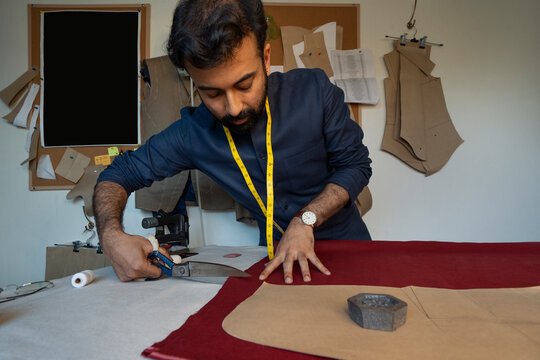 Male designer cutting fabric for a jacket in his studio 
