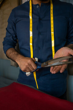 A bespoke tailor showing his tool - a fabric scissors 