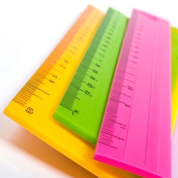 Colorful plastic school rulers stacked on a white background.