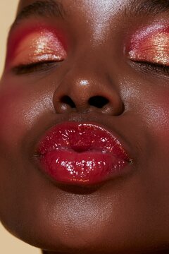 Extreme close-up of woman applying deep red lipstick. Beauty portrait showcasing bold makeup and flawless skin texture. Professional model demonstr...