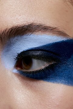 Close-up of woman's eye with blue eye shadow. Detailed view of eye makeup. Beauty and cosmetics concept.