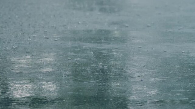 Close-up of raindrops splashing into a puddle during a rainy suburban storm. Captures the peaceful and dramatic moment of rainfall in high detail