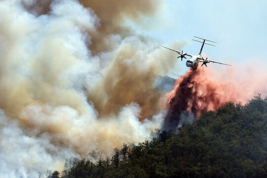 A firefighting plane drops a massive load of water over a raging wildfire burning near Ille-sur-Tet close to Perpignan in southern France as aerial crews battle to contain the devastating blaze.