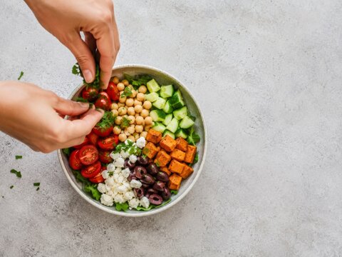 Preparaci&oacute;n de una ensalada saludable con varios ingredientes frescos en un taz&oacute;n grande