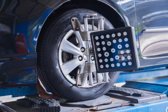 Wheel alignment sensor target attached to a car tire. Professional auto repair garage service for vehicle steering calibration and safety maintenance