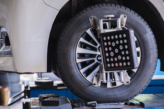 Wheel alignment sensor target attached to a car tire. Professional auto repair garage service for vehicle steering calibration and safety maintenance