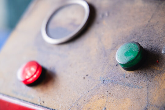 Illuminated green and red power indicator light on a dirty industrial machine panel. Active electrical equipment in an auto repair workshop or manufacturing factory