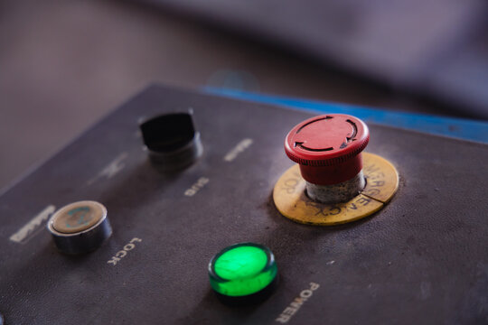 Red emergency stop button and main power switch on an industrial machine control panel. Essential safety equipment for factory or auto repair workshop operations