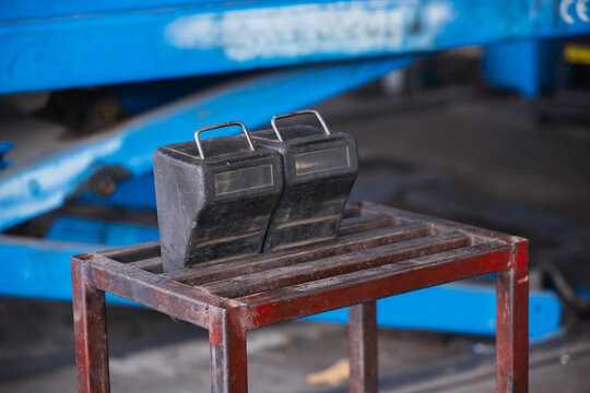 Heavy-duty black rubber wheel chocks resting on a metal stand in an auto repair garage. Essential vehicle immobilization and safety equipment for mechanic shops