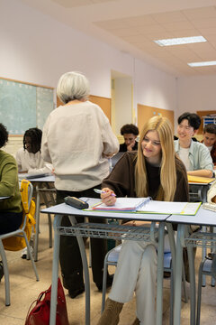 Teacher instructing a diverse group of high school students during a lesson in class