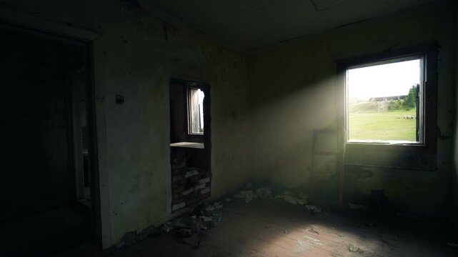 Sunlight streams through a window into a dark abandoned room, revealing dusty air, peeling walls, scattered debris, and an empty interior with a desolate mood