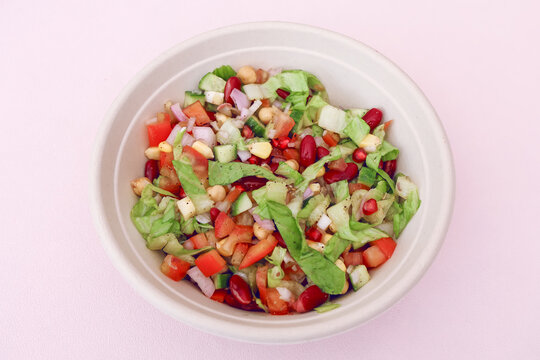 Fresh Healthy Mixed Vegetable Salad with Chickpeas, Kidney Beans, Corn and Pomegranate in White Bowl. Perfect for healthy eating, vegan and vegetarian diets, food blogs, and lifestyle concepts.