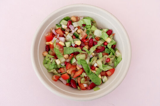 Fresh Healthy Mixed Vegetable Salad with Chickpeas, Kidney Beans, Corn and Pomegranate in White Bowl. Perfect for healthy eating, vegan and vegetarian diets, food blogs, and lifestyle concepts.