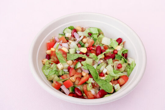 Fresh Healthy Mixed Vegetable Salad with Chickpeas, Kidney Beans, Corn and Pomegranate in White Bowl. Perfect for healthy eating, vegan and vegetarian diets, food blogs, and lifestyle concepts.