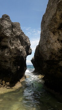 Narrow passage between large rocks leading to the ocean waves